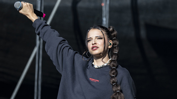 Sängerin Nina Chuba beim Musikfestival Juicy Beats steht auf der Bühne und streckt den rechten Arm nach oben.